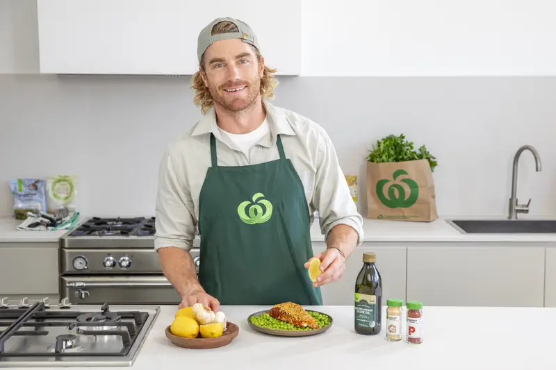 Hayden Quinn squeezing a lemon over a crumbed fish and peas dish