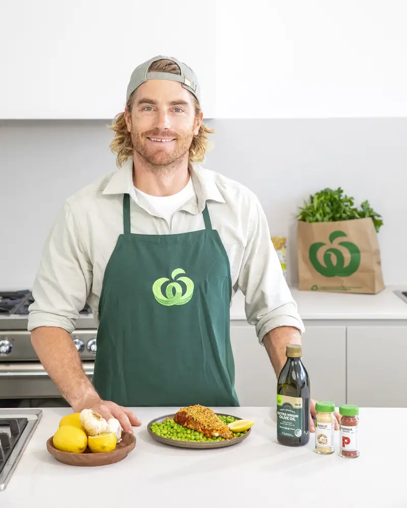 Hayden Quinn at a Woolworths bench, facing the camera with his hands on the counter