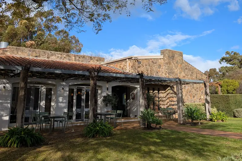 Low stone homestead behind a lawn and gum tree