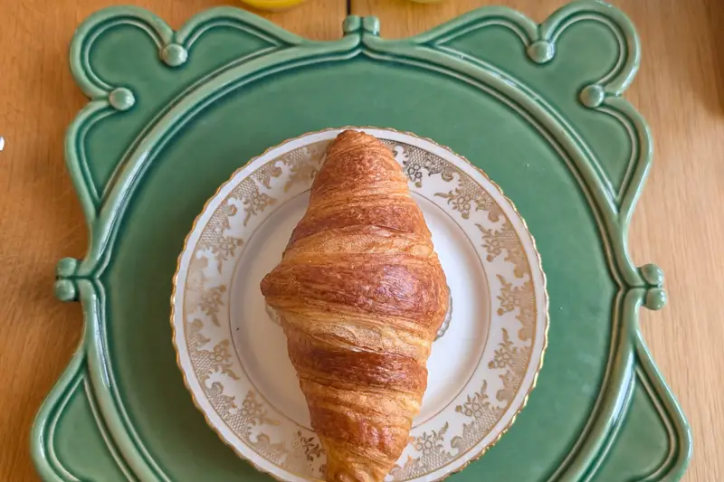 Croissant on a green patterned plate with juice glasses