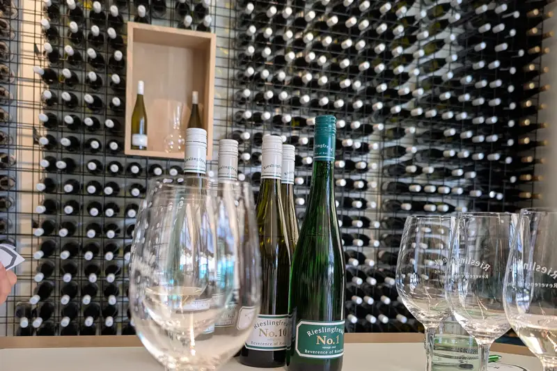 Wall of wine bottles behind a tasting table set with glasses