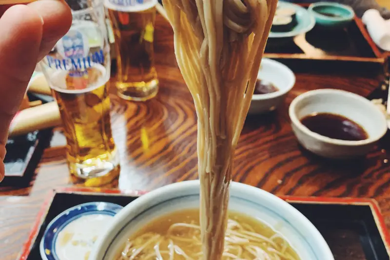 Chopsticks lifting noodles from a bowl of broth