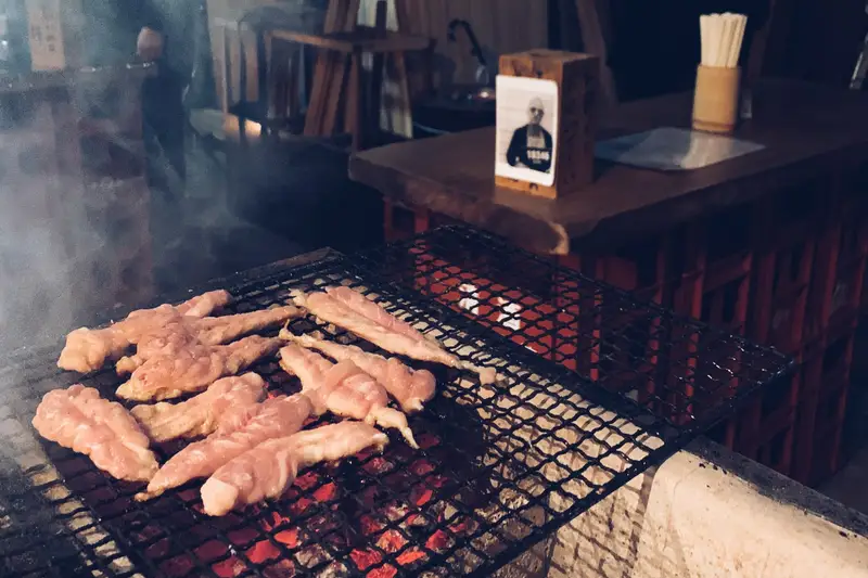 Meat cooking on a charcoal grill in a smoky restaurant