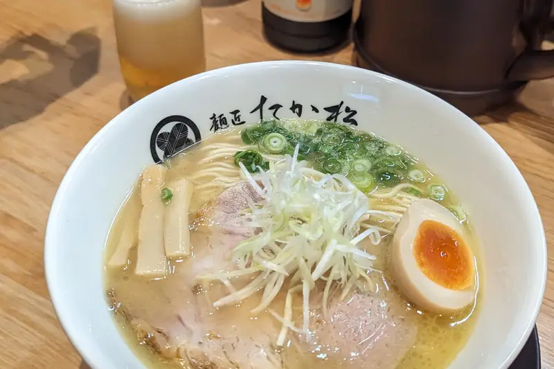 Bowl of ramen with a soft egg and sliced pork on a wooden counter