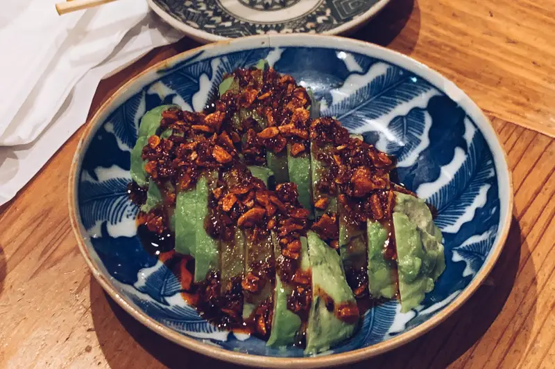 Greens topped with crispy chilli on a blue-and-white plate