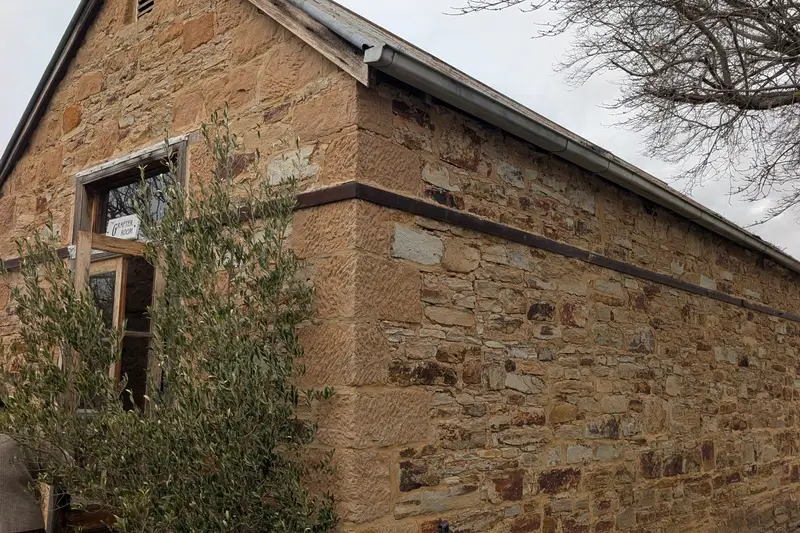 Old sandstone cottage beside a bare tree