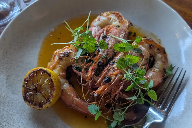 Plate of prawns with herbs and a charred lemon