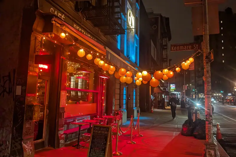 Restaurant front glowing red under hanging lanterns on a street at night