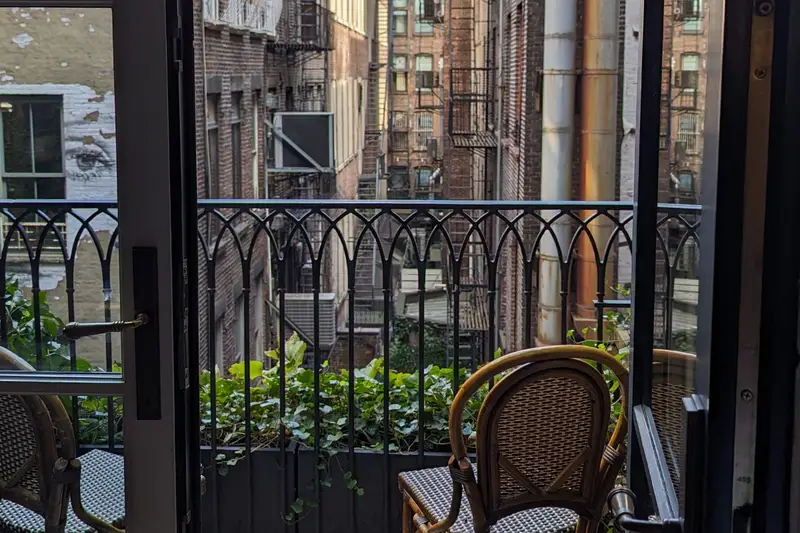 Open doors onto a small balcony overlooking a street of brick buildings