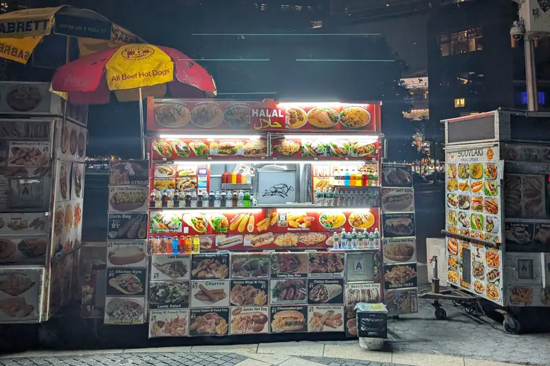 Food cart lit up on a dark street at night