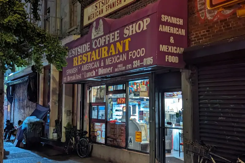 Lit coffee shop and restaurant signs on a street at night