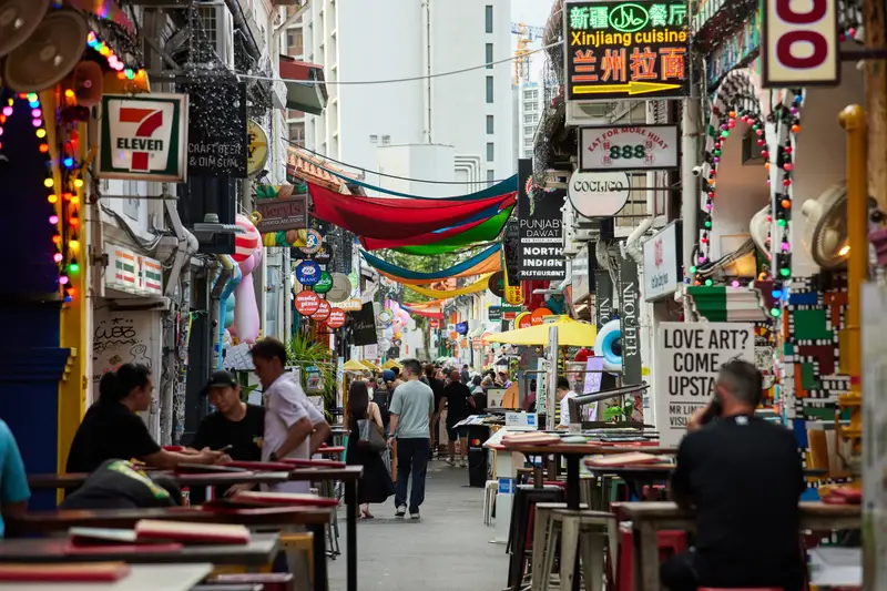 Lane of outdoor tables under shop signs and lanterns