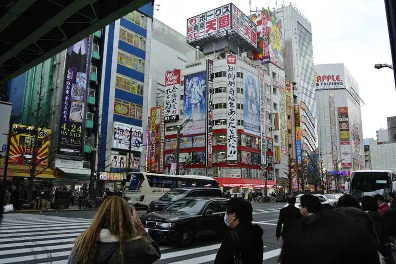 Busy Tokyo street crossing with crowds under bright shop signs and billboards