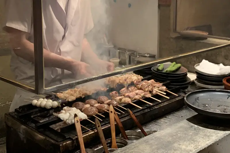 Skewers cooking over a smoky charcoal grill